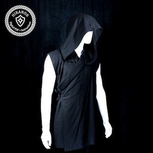 May include: Black sleeveless hooded tunic displayed on a mannequin. The tunic features a wrap-style front with a tie closure and a deep hood. The image includes a circular logo with the text "HIRANOR" and "Digital PDF + Instructions".