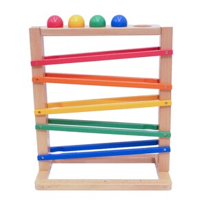 May include: A wooden toy with a series of colourful ramps and four coloured balls. The balls are red, yellow, green, and blue. The ramps are red, orange, yellow, green, and blue. The toy is designed for children to play with.
