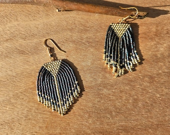 May include: A pair of gold and black beaded fringe earrings. The earrings are made with small, round beads and have a tassel-like design.