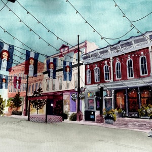 May include: A watercolour painting depicting a street scene with buildings, flags, and fairy lights. The buildings are painted in shades of red, brown, and white. The flags are blue, white, and red. The fairy lights are white and strung across the street. The scene is set in a small town or city.