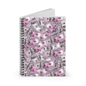 Peut inclure: Un carnet à spirales rose et blanc avec un motif de billets de dollars américains. Les billets sont roses et blancs et présentent un portrait de Benjamin Franklin.