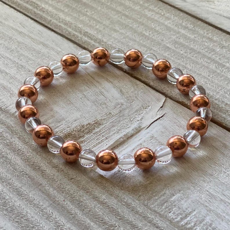 Pode incluir: Um bracelete feito de contas alternadas transparentes e de cor cobre. O bracelete &eacute; feito de pedras naturais e &eacute; projetado para ser usado no pulso.