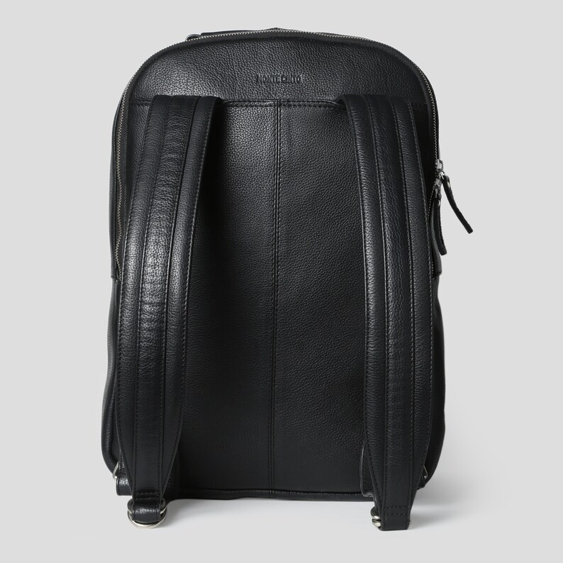 Puede incluir: Mochila de cuero negro con la parte superior redondeada y dos correas ajustables para los hombros. La mochila tiene un cierre de cremallera y un peque&ntilde;o bolsillo con cremallera en la parte delantera. La marca "MONTECITO" est&aacute; grabada en la parte superior.