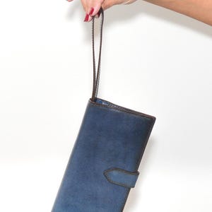 May include: A blue leather wallet with a brown strap. The wallet has a flap closure and a small pocket on the front.