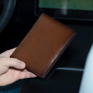 May include: A brown leather wallet with a smooth, textured surface.