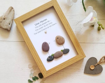 May include: A rectangular light wood frame containing white paper with the text: Dear Marilyn, You will always be... The sister of my soul, The best Friend of my heart. Two birds made of smooth brown and gray pebbles are depicted with ink lines.