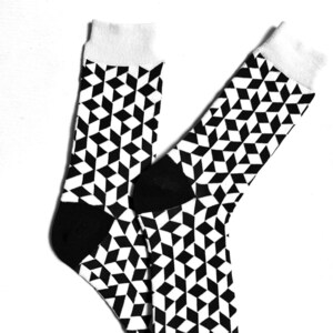 Könnte beinhalten: Ein Paar schwarz-weiße Socken mit geometrischem Muster. Die Socken sind aus weichem, bequemem Material gefertigt und haben eine schwarze Ferse und Spitze.