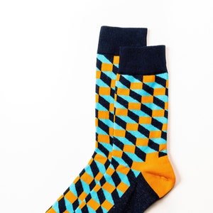 Könnte beinhalten: Ein Paar blaue und orangefarbene Socken mit geometrischem Muster. Die Socken sind aus weichem, bequemem Material gefertigt und perfekt für den Alltag.