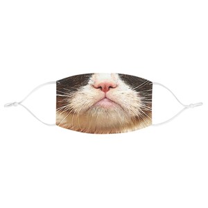 May include: A white face mask with a black and white cat face printed on it. The cat's nose is pink and its mouth is closed.