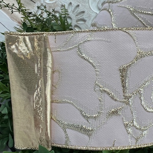 Closenup of pale pink ribbon with gold roses.