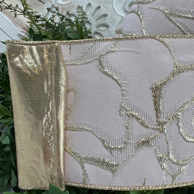 Closenup of pale pink ribbon with gold roses.