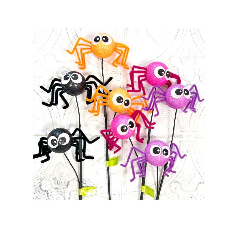 May include: A collection of colorful, glittery spider decorations on black stems. The spiders are in various colors, including orange, pink, purple, and black, with large googly eyes. These Halloween-themed decorations are perfect for adding a spooky touch.