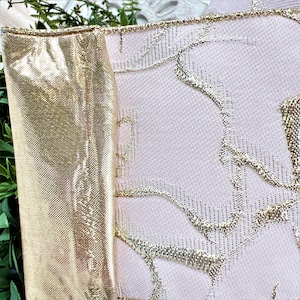 Closenup of pale pink ribbon with gold roses.