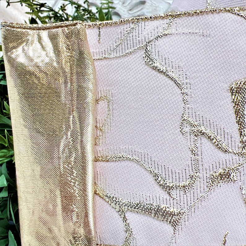 Closenup of pale pink ribbon with gold roses.