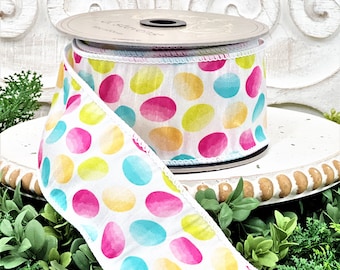 May include: A white ribbon with a colorful polka dot pattern. The dots are in shades of pink, yellow, blue, and green. The ribbon has a white edge.
