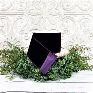 A 4" roll of dark purple velvet sits on a white wood pedestal surrounded by greenery.