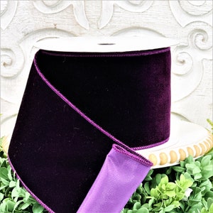 A 4" roll of dark purple velvet sits on a white wood pedestal surrounded by greenery.