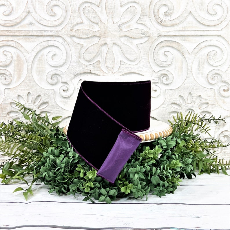 A 4" roll of dark purple velvet sits on a white wood pedestal surrounded by greenery.