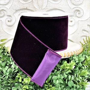 A 4" roll of dark purple velvet sits on a white wood pedestal surrounded by greenery.