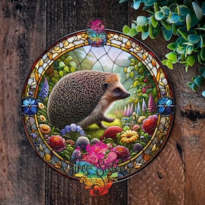 A round metal faux stained glass design depicting a hedgehog in a garden setting. The hedgehog is brown and black with a light brown nose and is surrounded by colourful flowers and leaves. The stained glass design is framed in a black metal frame. Is suitable for outdoor and indoor use as it is weatherproof so can be used as a garden ornament, outdoor wall art, as a unique gift, House plaque or wreath sign