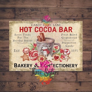 A vintage-style metal sign for a Hot Cocoa Bar, with a mug of cocoa, gingerbread biscuits, and candy canes. The sign includes text that reads "Candy Cane Lane" and "Bakery & Confectionery." The sign is displayed on a wooden fence