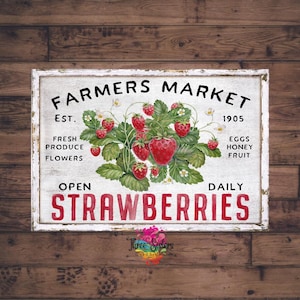 May include: A white sign with distressed edges and red lettering reads "Farmers Market Est. 1905 Open Daily Strawberries". The sign features a watercolour illustration of a strawberry plant with red strawberries and green leaves.