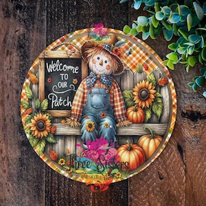 May include: A round, wooden sign with a plaid background and a scarecrow sitting on a fence. The sign says "Welcome to our Patch" and features sunflowers, pumpkins, and autumn foliage.