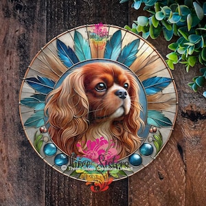 May include: Circular wall art depicting a Cavalier King Charles Spaniel with brown fur. The dog is framed by blue feathers and blue glass beads. The artwork includes the text "Three Sisters Creations Limited".