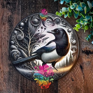 May include: A black and white magpie with a long tail perched on a branch in a circular, ornate, silver frame. The background is a forest scene with trees and a sky.
