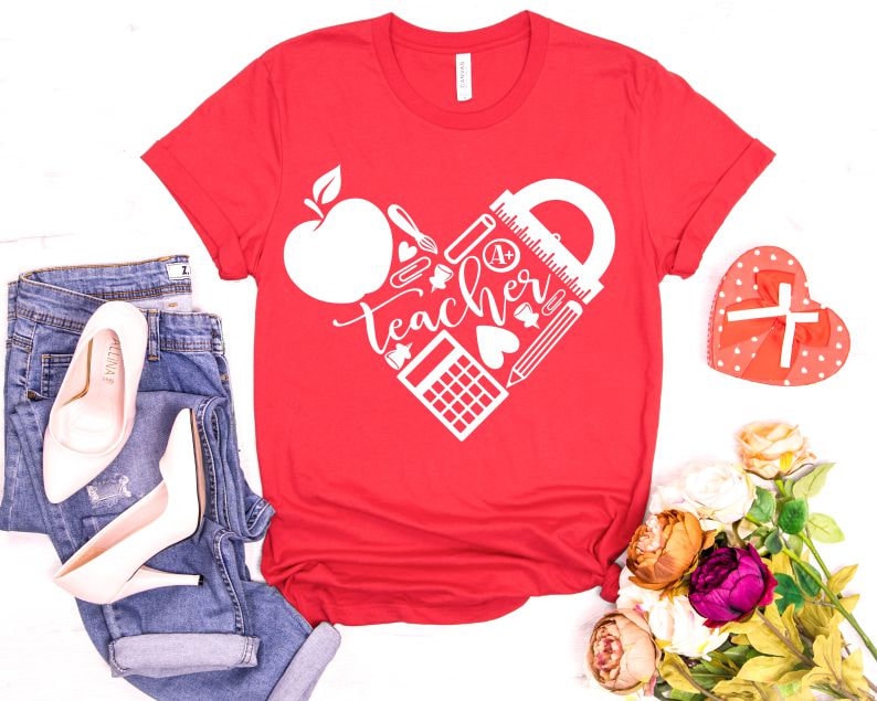 Peut inclure: T-shirt rouge avec un motif de c&oelig;ur blanc repr&eacute;sentant le mot "Teacher" et des fournitures scolaires comme une r&egrave;gle, un crayon et une calculatrice.