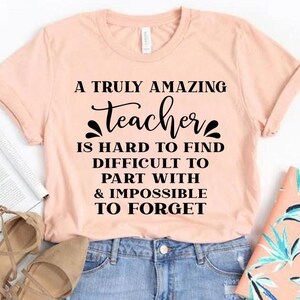 Peut inclure: Un t-shirt rose avec un motif noir qui dit "Un professeur vraiment incroyable est difficile &agrave; trouver, difficile &agrave; quitter et impossible &agrave; oublier."