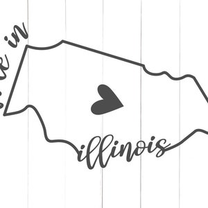 Może przedstawiać: Czarno-biały projekt graficzny stanu Illinois z sercem w środku i tekstem "made in" po lewej stronie oraz "illinois" pod zarysowaniem stanu.