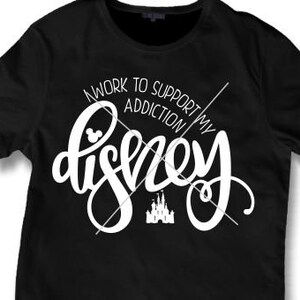 May include: Black t-shirt with white text that reads "I work to support my Disney addiction". The text is in a stylized font and includes a Mickey Mouse head and a silhouette of Cinderella's castle.