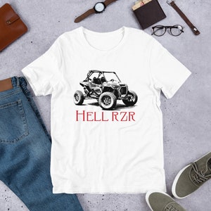 Puede incluir: Camiseta blanca con una ilustración en blanco y negro de un vehículo todoterreno y el texto "HELL RZR" en rojo.