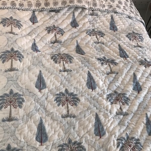 May include: White cotton quilt with a repeating pattern of blue palm trees and small blue trees. The quilt is quilted in a diamond pattern.