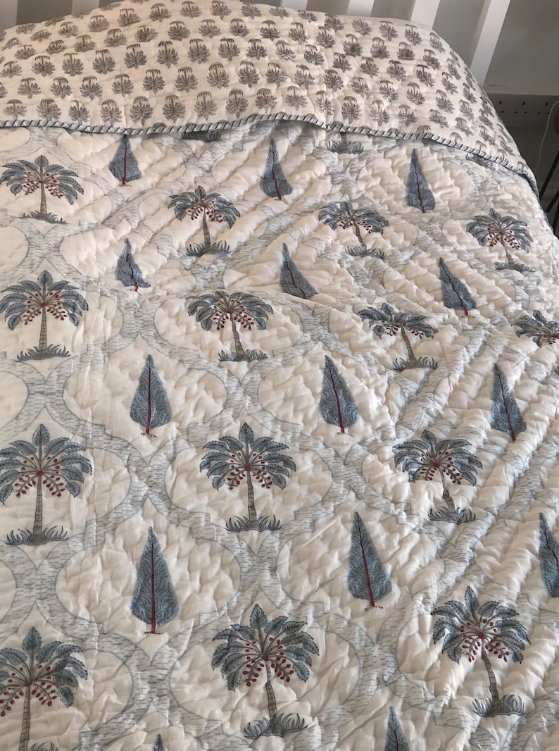 May include: White cotton quilt with a repeating pattern of blue palm trees and small blue trees. The quilt is quilted in a diamond pattern.