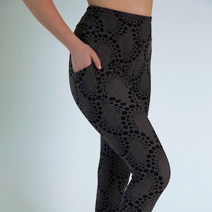 May include: Black and brown leggings with a high waist and a pocket on the left side. The leggings have a swirling pattern of black dots on a brown background.