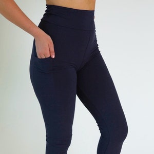 May include: Navy blue leggings with a high waist and a single pocket on the left leg.