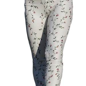 May include: White leggings with a floral print of pink flowers and green vines.