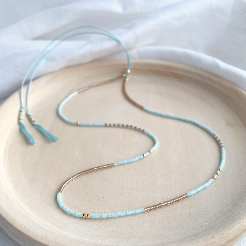 Delicate ice blue and gold beaded necklace on a blue silk thread with a gold slider bead