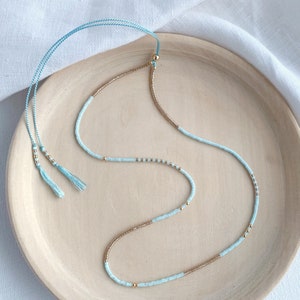 Dainty beaded necklace with pale blue and gold glass miyuki delicate beads on a light blue silk thread with an adjustable slider clasp