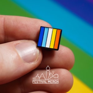 May include: A small square enamel pin with a rainbow design. The pin has five stripes: blue, light blue, white, yellow, and orange. The pin is black outlined.