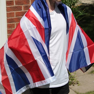 Puede incluir: Una persona con una camiseta blanca envuelta en una bandera británica roja, blanca y azul.