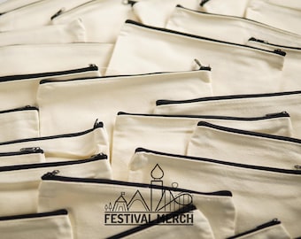 May include: A stack of off-white canvas pouches with black zipper closures. The pouches are blank except for the bottom pouch which has the text "FESTIVAL MERCH" printed in black.