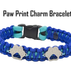 May include: Blue and turquoise paracord bracelet with two silver paw print charms. "Paw Print Charm Bracelet" is written above the bracelet.