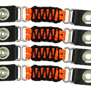 May include: Four black leather straps with orange and black braided cord, each with a silver snap button on one end and a silver loop on the other end.