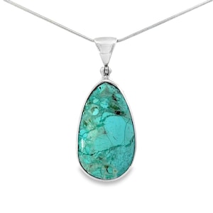 Puede incluir: Un colgante en forma de lágrima con una vibrante piedra turquesa, engastada en metal plateado. La piedra tiene un patrón veteado único de azules y verdes. El colgante cuelga de una delicada cadena plateada.