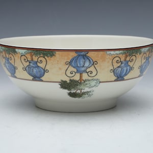 May include: A white ceramic bowl with a blue and yellow floral design. The bowl has a wide rim and a rounded bottom.
