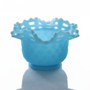 May include: A light blue glass bowl with a scalloped edge and a lattice design. The bowl is made of milk glass and has a vintage look.