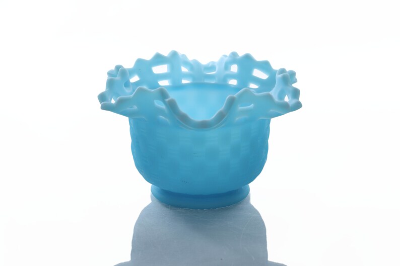 May include: A light blue glass bowl with a scalloped edge and a lattice design. The bowl is made of milk glass and has a vintage look.